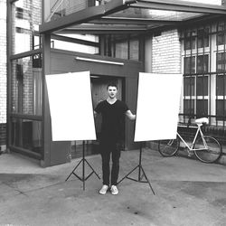 Full length of man holding whiteboards in courtyard