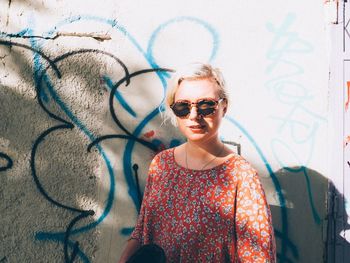 Portrait of woman standing against graffiti