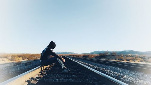 Man on railroad track against sky