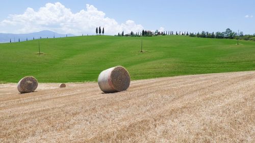 Hay bales on field against sky