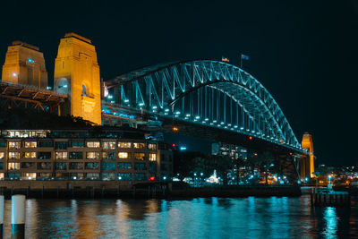 Illuminated bridge over river at night