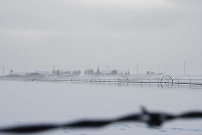 Agricultural machinery on snow covered field against sky