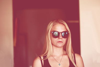 Young woman wearing sunglasses by wall