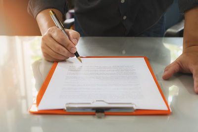 Midsection of businessman reading document on desk in office