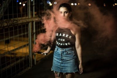 Woman standing against illuminated wall at night