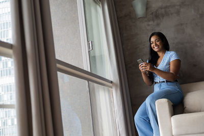 Young black woman working at home with smartphone on her couch in the living room. home office 