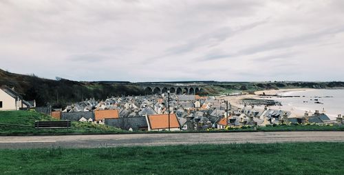 Houses on field by buildings against sky