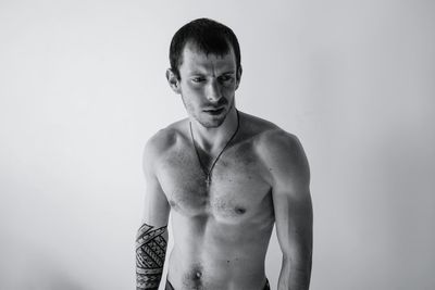 Young shirtless man standing against white background