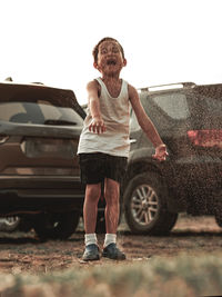 Full length of teenage girl standing on car against sky