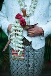 Midsection of woman holding white flower