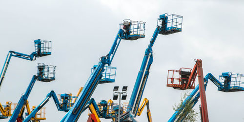 Low angle view of cranes against sky