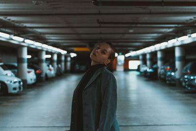 Young woman looking away while standing in parking lot