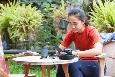 Young woman looking down while sitting on table
