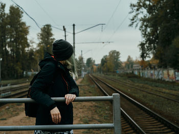 Woman standing by railing at railroad station