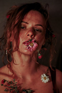 Close-up portrait of beautiful woman with flowers in mouth