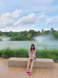 Portrait of young woman standing against waterfall