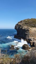 Rock formation on beach against clear blue sky