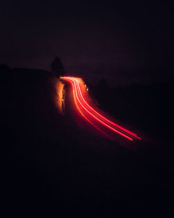Light trails on road against sky at night