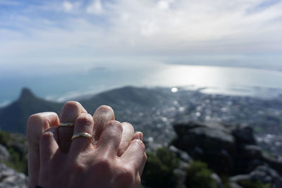 Midsection of person on rock by sea against sky