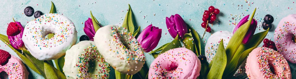 High angle view of donuts with tulips and fruits on table