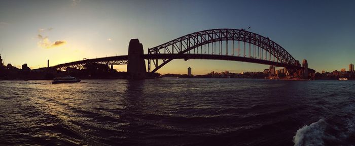 Suspension bridge over river during sunset