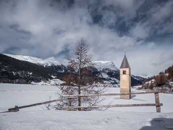 Church by snow covered trees against sky