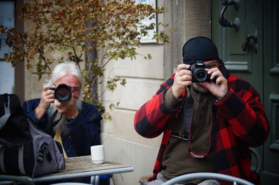 Full length of man photographing while using smart phone