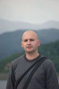 Portrait of bald man standing against mountain