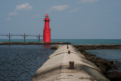 Lighthouse by sea against sky