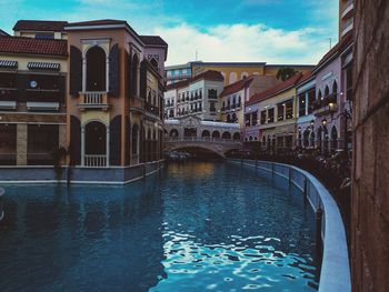 Bridge over canal amidst buildings in city against sky