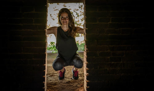 Portrait of young woman standing against brick wall