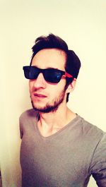 Portrait of young man wearing sunglasses against white background
