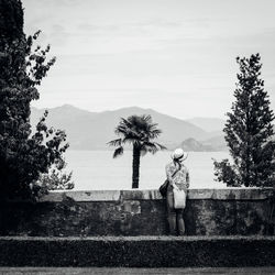 Rear view of woman looking at lake against sky