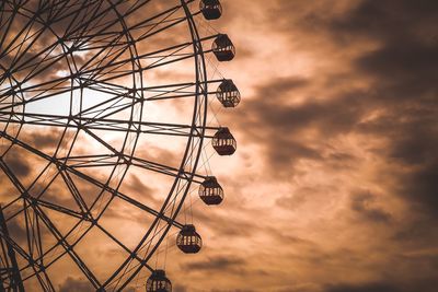 Low angle view of ferris wheel against cloudy sky