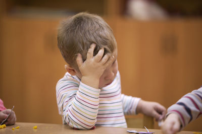 Close-up of worried boy sitting on table at classroom