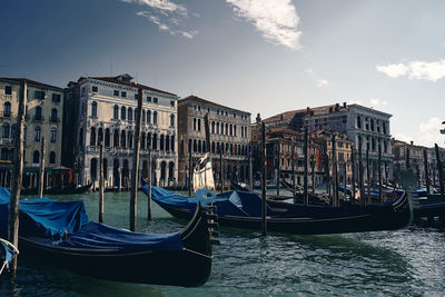 Boats moored at canal against buildings in city