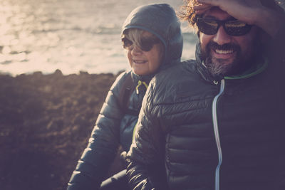 Couple sitting at beach against blue sky