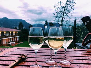 Close-up of wine glasses on table against sky