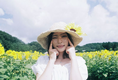 Portrait of man wearing hat standing against yellow flowers