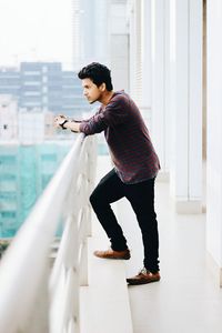 Side view of handsome young man standing at building balcony