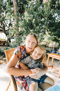 Portrait of mature woman with granddaughter sitting on chair