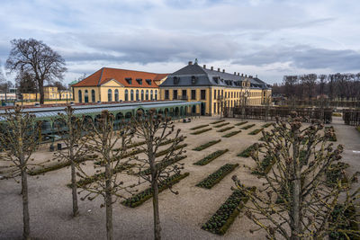 House by trees and buildings against sky