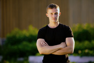 Young man looking away while standing outdoors