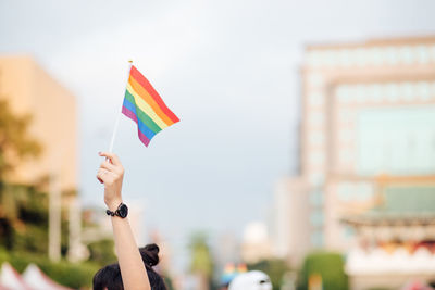 Low angle view of hand holding rainbow flag at lgbt pride parade