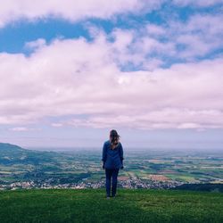 Woman on landscape against cloudy sky