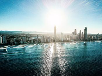 Sea by modern buildings against clear sky