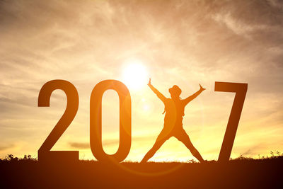 Silhouette person jumping amidst numbers on field against sky during sunset