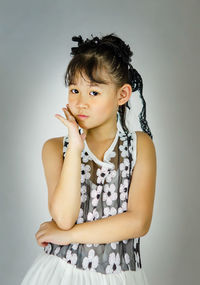Portrait of girl standing against gray background