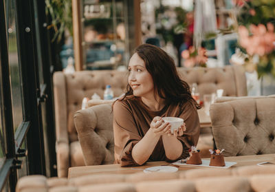 Young woman looking at camera while sitting on table