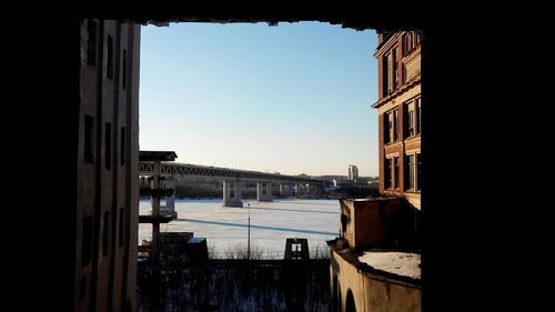 Buildings by sea against clear sky seen through window